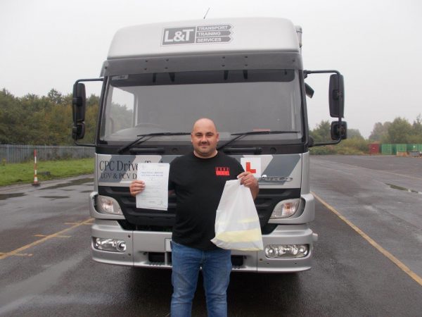 A photo of Andy Bardsley with an L&T vehicle and his pass certificate